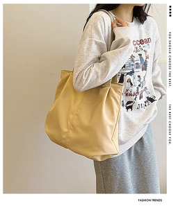 Detail of spacious beige canvas tote bag showing smooth fabric and wide shoulder strap