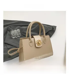 Détail du sac cabas beige avec texture crocodile et fermoir en métal fleur dorée