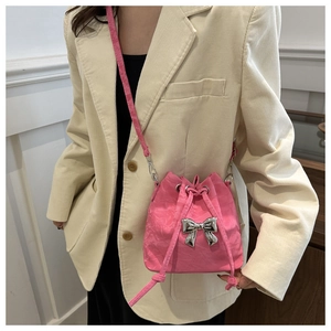 Close-up of pink pleated bucket bag with silver bow ornament and drawstring closure