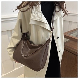 Détail d'un sac bandoulière en cuir grainé marron avec chaîne dorée et bandoulière