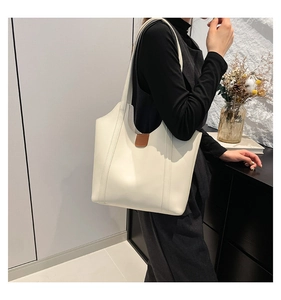 Detailansicht einer großen weißen Ledertasche mit braunem Verschluss und langen Riemen