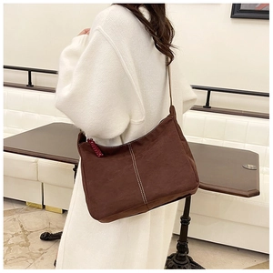 Vue détaillée du sac cabas en daim marron avec coutures contrastées sur pull blanc