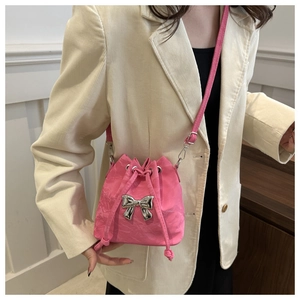 Detail of a bright pink drawstring bucket bag with a stylish silver metallic bow ornament