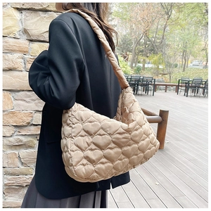 Detail of camel quilted tote bag featuring heart pattern stitching and wide strap