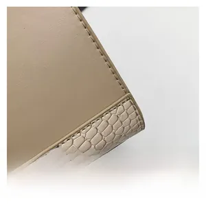 Gros plan d'un cabas beige en similicuir avec texture serpent et coutures fines