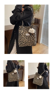Detail view of leopard print canvas tote bag with plush charm and woven letter patch