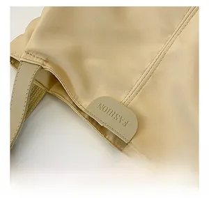 Close-up of beige canvas tote bag with reinforced double stitching and leather logo detail