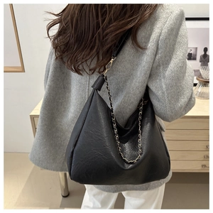 Détail du sac hobo en cuir noir grainé avec chaîne dorée et bandoulière large