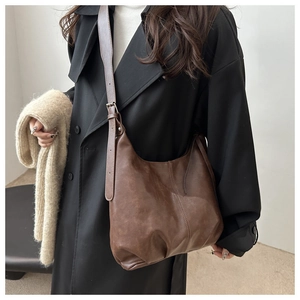 Detail of vintage dark brown faux leather shoulder bag worn over a black wool coat