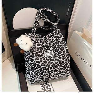 Close-up of leopard print tote bag with white plush charm and woven label detail