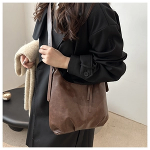 Detailed view of dark brown vintage leather shoulder bag styled with a black winter coat