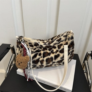 Sac fourre-tout en peluche léopard avec breloque ours et lanières blanches sur une chaise