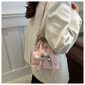 Detail showing the light pink drawstring bucket bag with a silver bow and thin shoulder strap