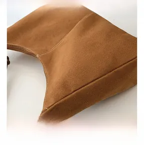 Détail d'un sac hobo en daim marron avec surpiqûres et boucle métallique réglable