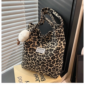Detail of leopard print nylon tote bag with plush charm on vintage books background
