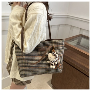 Detailansicht der großen Karo-Stofftasche mit braunen Lederriemen und Plüsch-Katzenanhänger