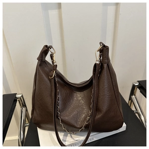 Détail de la texture en similicuir marron foncé et de la chaîne dorée sur le sac cabas