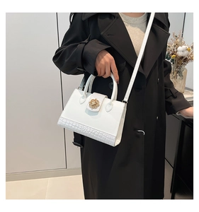 Détail du sac cabas blanc avec motif crocodile et boucle dorée en forme de fleur