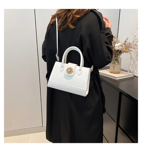 Détail du sac blanc avec boucle florale dorée sur base en texture crocodile