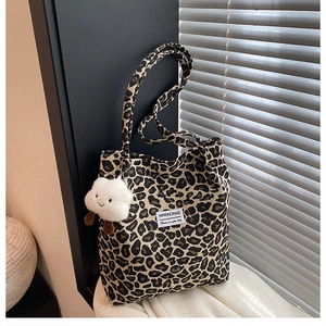 Close-up of leopard print nylon tote bag with plush cloud charm and white woven label