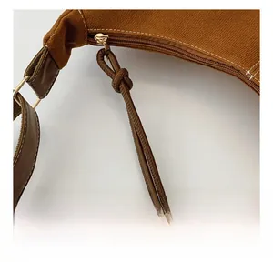 Détail d'une fermeture éclair dorée et d'un tissu texturé marron sur un sac vintage