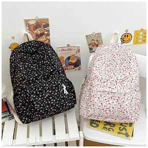 Detailed view of floral canvas backpacks in black and white styles on a rustic chair