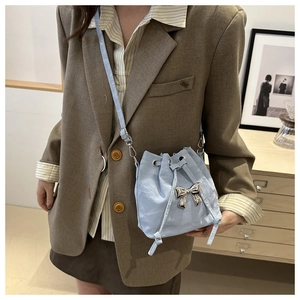 Detail of light blue pleated bucket bag with silver metal bow and drawstring closure