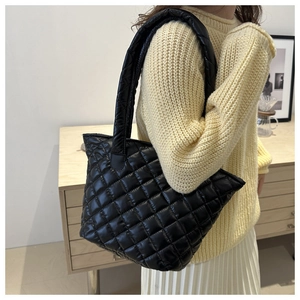 Detailed view of the black quilted tote bag texture and soft nylon shoulder strap