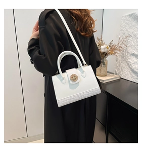 Détail du sac blanc montrant la texture crocodile et la boucle en métal doré floral