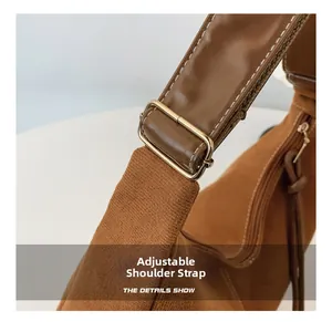 Détail de la bandoulière réglable en cuir marron avec boucle en métal doré et surpiqûres