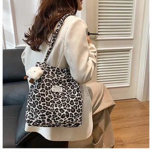 Lifestyle shot of large leopard print tote bag featuring plush sheep pendant detail
