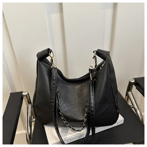 Détail de la texture en cuir grainé noir sur un sac hobo avec des accents de chaîne