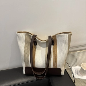Detail view of large canvas tote bag with brown stripes and reinforced leather corners