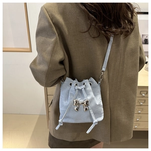 Detail of light blue pleated bucket bag with silver metal bow and drawstring strap