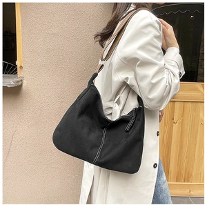 Détail du sac fourre-tout noir avec surpiqûres blanches et bandoulière en cuir marron