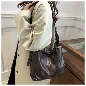 Detail of dark brown faux leather shoulder bag featuring side fringe drawstring and strap