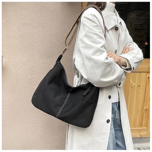 Détail du sac hobo en toile noire avec surpiqûres blanches et bandoulière marron