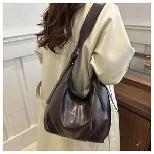 Detail of dark brown faux leather tote showing the wide strap and smooth material texture