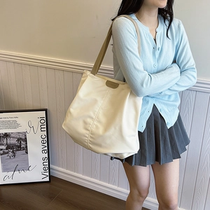 Close-up of a cream canvas tote bag with a khaki strap and leather Fashion tag