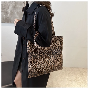 Vue de profil d'un grand sac cabas à imprimé léopard porté avec un trench-coat noir chic