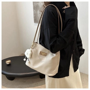 Détail du sac fourre-tout beige gaufré avec breloque nuage en peluche et logo en cuir