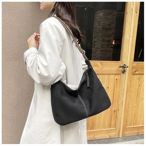 Détail du sac Hobo en toile noire avec surpiqûres blanches et bandoulière en cuir marron