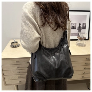 Close-up of black leather shoulder bag showing smooth texture and zipper detail
