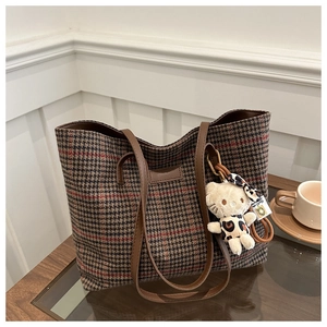 Detail der Houndstooth-Tasche mit braunen Griffen und Leoparden-Anhänger