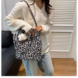 Detailed view of black and white leopard print tote bag with plush cloud charm and strap