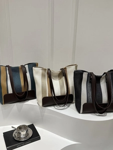 Detailed view of striped canvas tote bags with leather handles in three various colors