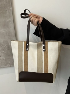 Close-up of striped canvas tote bag showing khaki and yellow fabric texture and leather handles