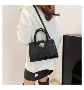 Détail du cabas noir vintage avec boucle florale dorée et texture crocodile gaufrée