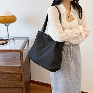 Fashion tag detail on large black nylon tote bag with high-density stitching texture