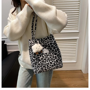 Detail of vintage leopard print tote bag with white fluffy cloud charm on shoulder